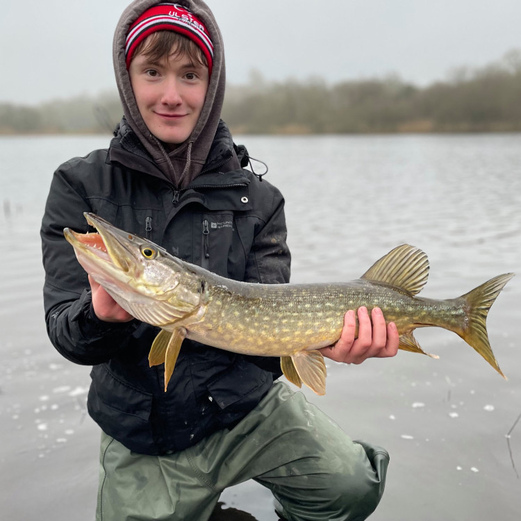 Young male kneeling in water holding a fish
